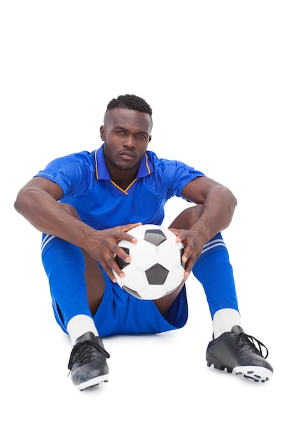 Photo joueur de football en bleu assis avec ballon