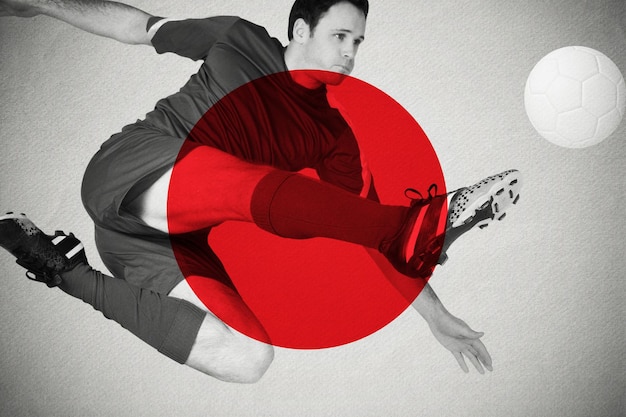 Joueur de football en bleu donnant des coups de pied contre le drapeau national du japon