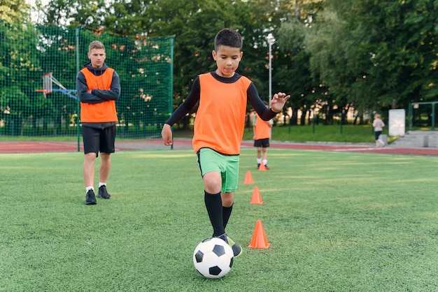 Joueur de football botter le ballon sur le terrain. Joueurs de football en séance d'entraînement. Footballeur adolescent coups de pied