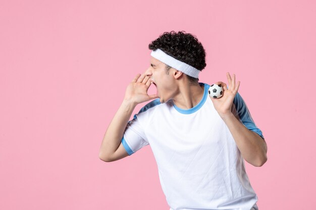 Joueur de football crier vue de face dans des vêtements de sport avec petite balle