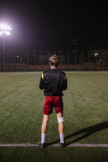 Photo joueur de football faisant des exercices d'échauffement sur le terrain avant le match de nuit