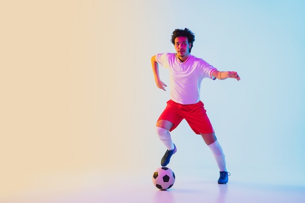 Joueur de football ou de football sur fond dégradé dans le concept d'activité d'action de mouvement de lumière au néon