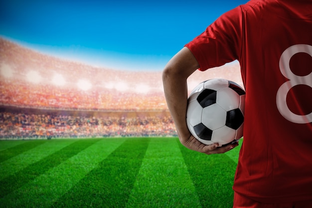 Photo joueur de football de football no.8 dans le concept de l'équipe rouge tenant le ballon de football dans le stade