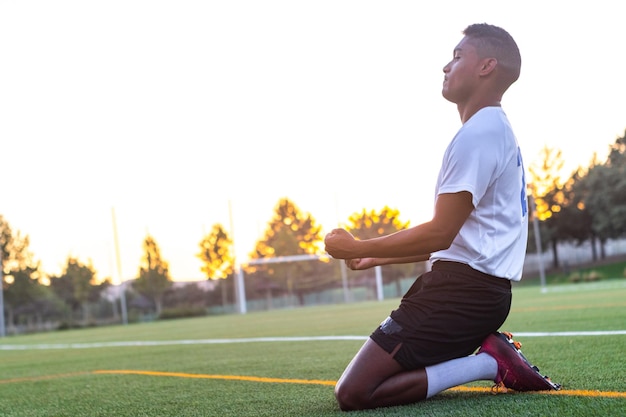 Joueur de football à genoux célébrant un but Homme footballeur excité célébrant un but