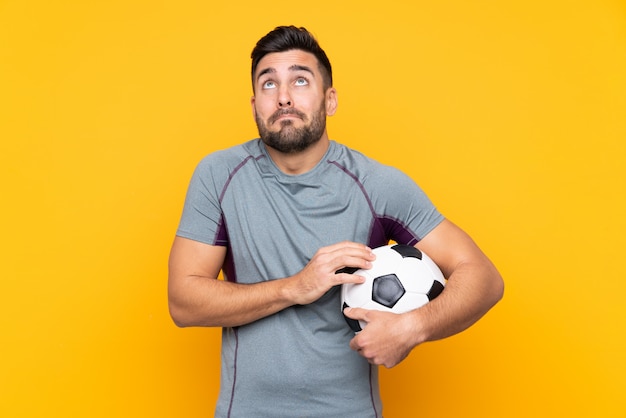 Joueur de football homme sur mur isolé faisant des doutes geste tout en soulevant les épaules