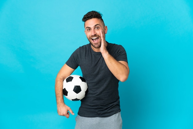 Joueur de football isolé sur fond bleu avec une expression faciale surprise et choquée