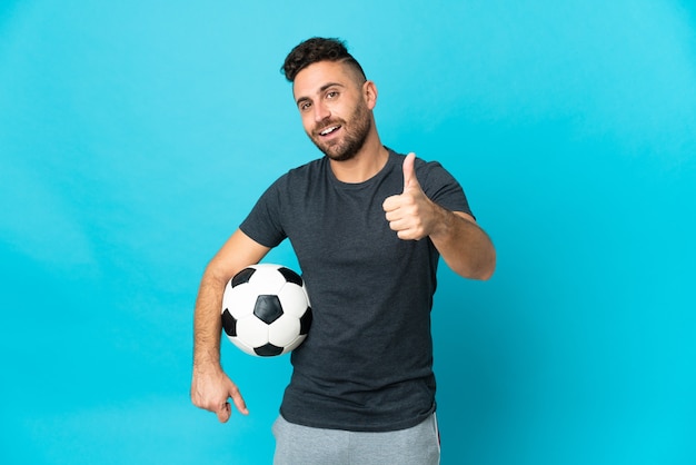 Joueur de football isolé sur fond bleu avec le pouce levé parce que quelque chose de bien s'est produit