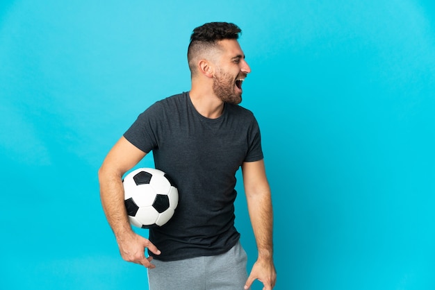 Joueur de football isolé sur fond bleu en riant en position latérale