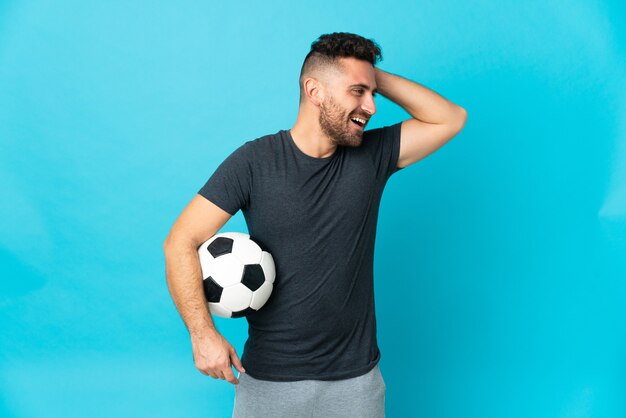 Joueur de football isolé sur fond bleu souriant beaucoup