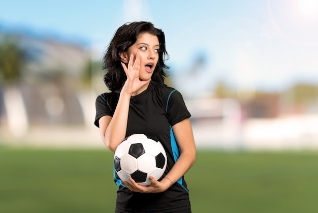 Joueur de football jeune femme criant avec la bouche grande ouverte à l'extérieur