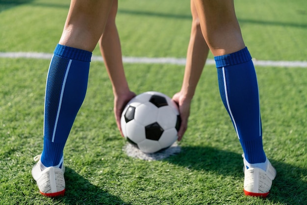 Un joueur de football a placé le ballon de football au point de coup franc avant de tirer un but dans le stade de football