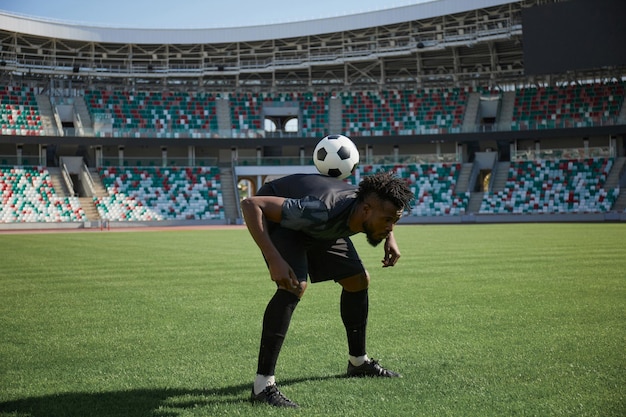 Un joueur de football s'entraîne en tenant le ballon avec son dos