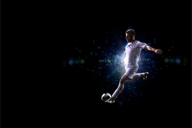 Un joueur de football en uniforme blanc frappe un ballon de football.