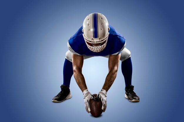 Joueur de football avec un uniforme bleu sur la ligne de mêlée sur un mur bleu