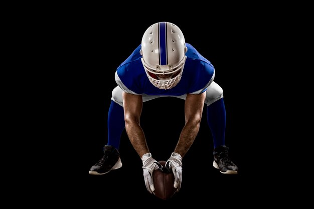 Joueur de football avec un uniforme bleu sur la ligne de mêlée sur un mur noir