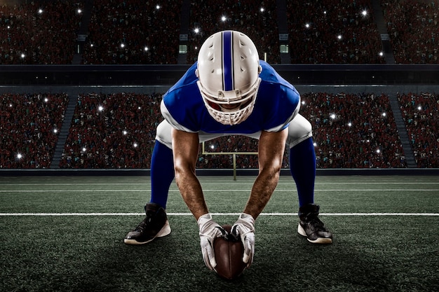 Joueur de football avec un uniforme bleu sur la ligne de mêlée sur un stade