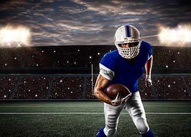 Joueur de football avec un uniforme bleu s'exécutant sur un stade