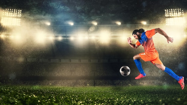 Joueur de football en uniforme orange et bleu sprintant rapidement avec le ballon au stade