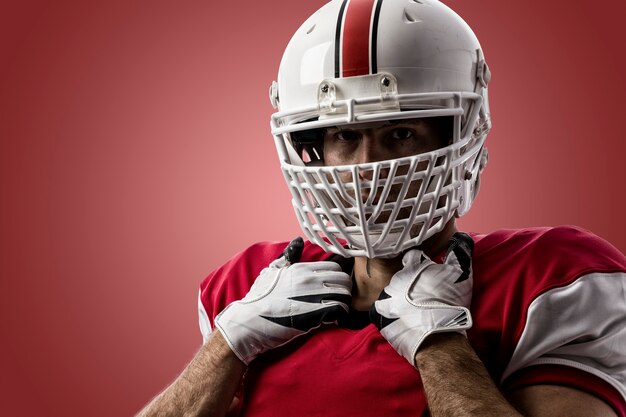 Joueur de football avec un uniforme rouge sur un mur rouge