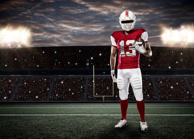 Joueur de football avec un uniforme rouge sur un stade.