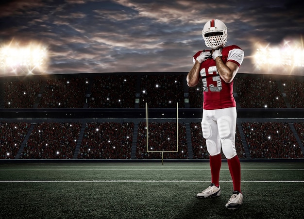 Joueur de football avec un uniforme rouge sur un stade.