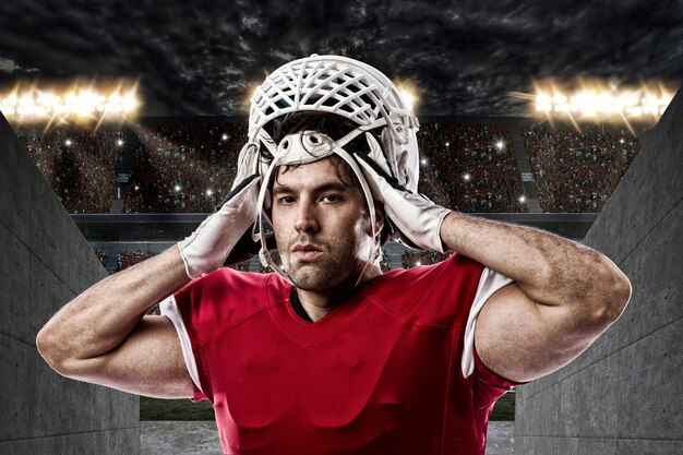 Joueur de football avec un uniforme rouge sur un tunnel du stade.