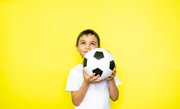 Le joueur de garçon de sport de ventilateur tient le ballon de football dans le t-shirt blanc célébrant le rire souriant heureux montrer les pouces