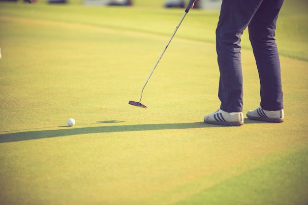 Joueur de golf au putting green frapper la balle dans un trou.vintage couleur