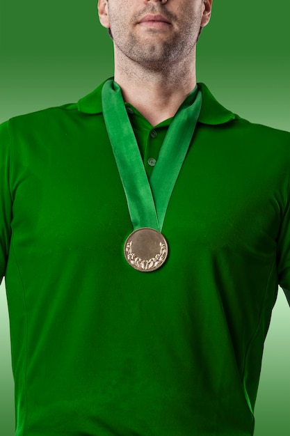 Joueur de golf dans une chemise verte célébrant avec une médaille d'or, sur fond vert.