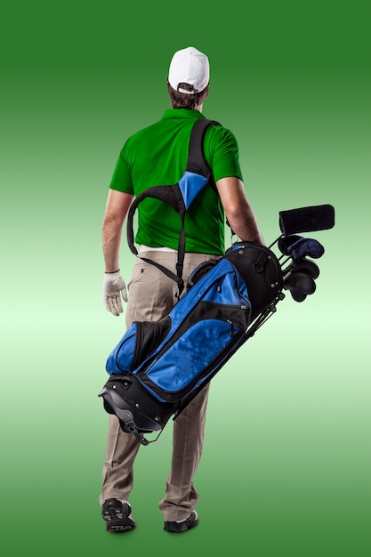 Joueur de golf dans une chemise verte marchant avec un sac de clubs de golf sur le dos, sur un fond vert.