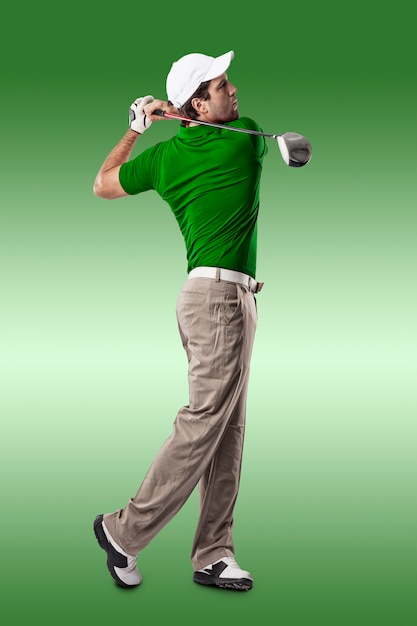 Joueur de golf dans une chemise verte prenant un swing, sur un fond vert.