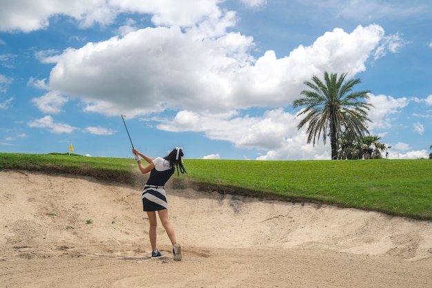 Joueur de golf féminin jouant le sable tourné en parcours de golf professionnel