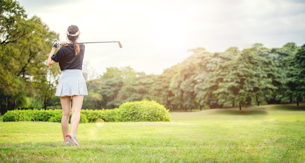 Joueur de golf de femme asiatique balançant le club de golf sur le fairway