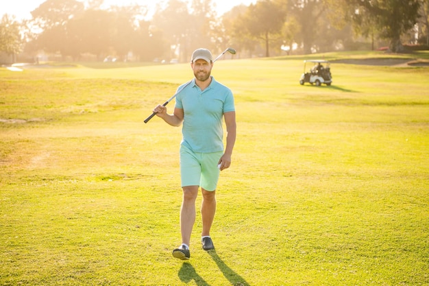 Joueur de golf masculin sur le parcours professionnel à pied sur le golf d'herbe verte