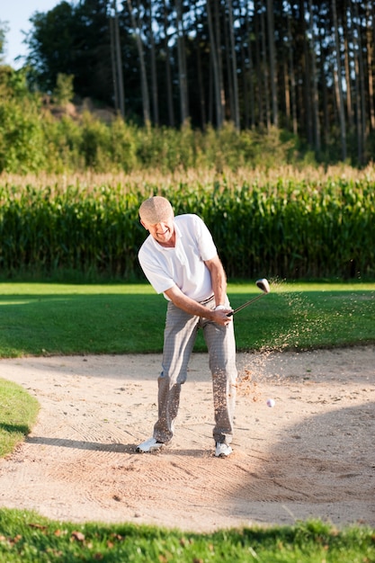 Joueur de golf senior dans un bac à sable