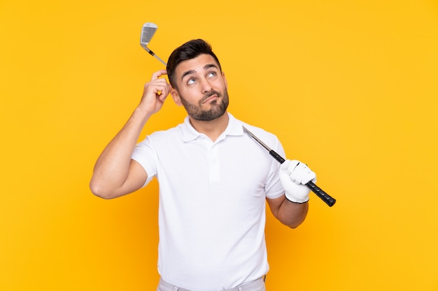 Joueur de golfeur homme sur mur jaune isolé ayant des doutes et avec une expression de visage confuse