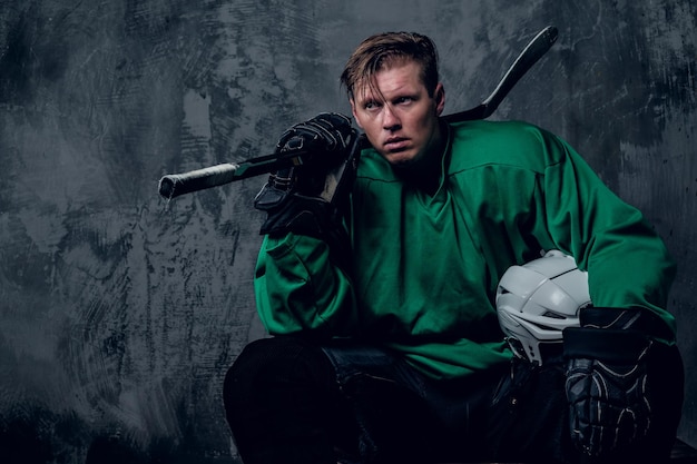 Joueur de hockey fatigué relaxant sur fond gris.