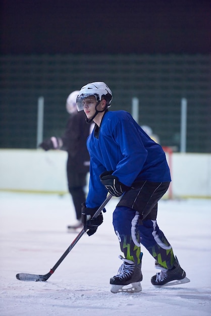 Photo joueur de hockey sur glace en action donnant des coups de pied avec un bâton