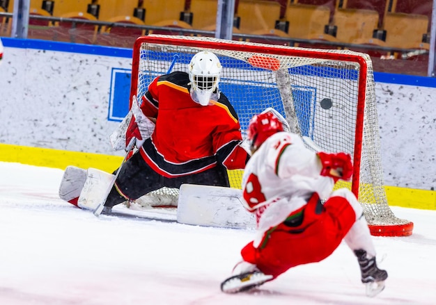 Photo un joueur de hockey sur glace essaie de marquer avec un tir frappé et un genou sur la glace
