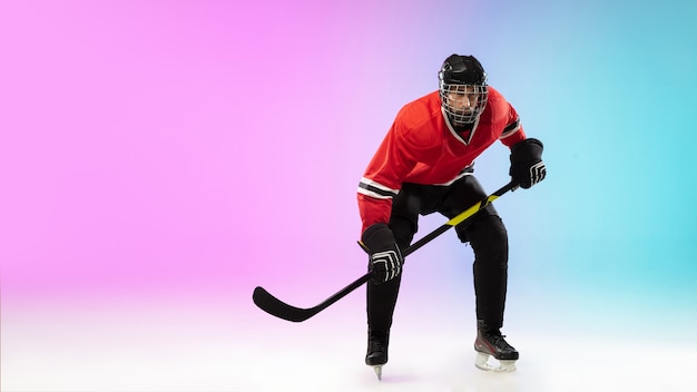 Joueur de hockey masculin avec le bâton sur la glace et sportif de mur dégradé de couleur néon vêtu...