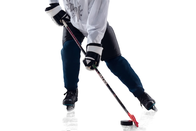 Joueur de hockey masculin méconnaissable avec le bâton sur la cour de glace et le fond blanc