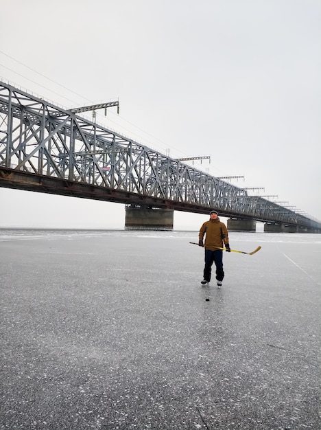 Joueur de hockey sur la Volga avec un bâton dans le contexte d'un grand pont à Oulianovsk