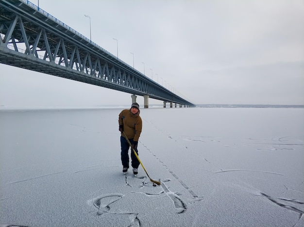 Joueur de hockey sur la Volga en toile de fond d'un grand pont à Oulianovsk