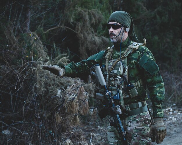 Joueur de jeu militaire Airsoft en uniforme de camouflage avec fusil d'assaut armé.