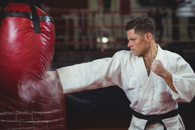 Joueur de karaté pratiquant le karaté avec sac de boxe