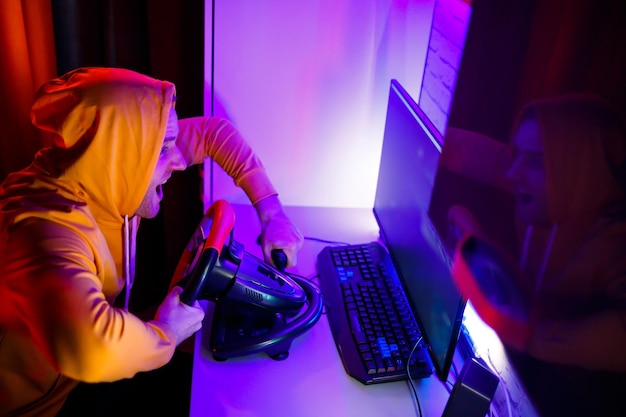 Joueur masculin jouant à des jeux de course sur l'ordinateur Il utilise le volant Jeu émotionnel