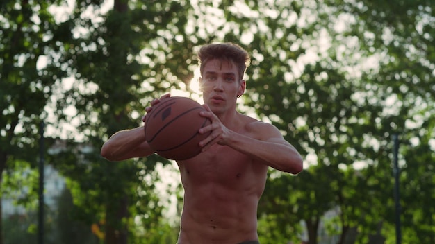 Joueur musclé concentré pratiquant le basket-ball de rue dans un terrain de sport