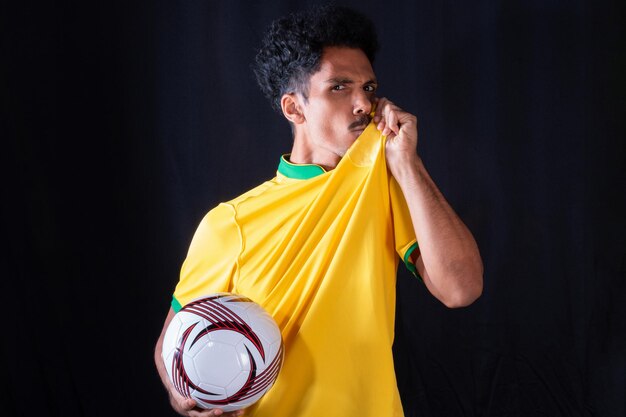 Joueur noir de football brésilien tenant le ballon et célébrant