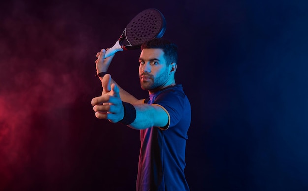 Joueur de padel avec raquette Athlète homme avec raquette sur le terrain avec des couleurs fluo Concept sportif Téléchargez une photo de haute qualité pour la conception d'une application sportive ou d'un site de paris