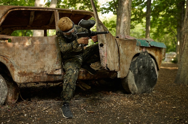 Joueur de paintball en uniforme et masque en forêt